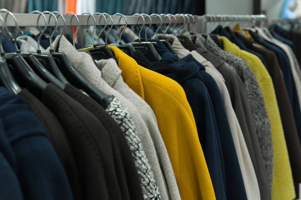 Ряд осенних пальто висит на стойке, шоппинг
 - Фото, изображение