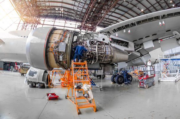 Mecánico especialista repara el mantenimiento de un gran motor de un avión de pasajeros en un hangar
. - Foto, Imagen