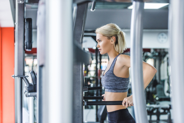 femme attrayante dans les vêtements de sport modernes faire de l'exercice sur pousser les barres à la salle de gym
 - Photo, image