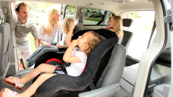 Padres poniendo asientos de coche familiares para niños
 - Imágenes, Vídeo