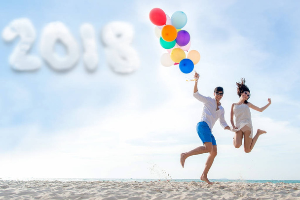 Yeni yıl 2018. Balon tutarak ve birlikte sahilde atlama gülümseyen iki el. Sevgilisi romantik ve yeni yıl rahatla. Yaz, seyahat, tatil, Sevgililer, kavram - Fotoğraf, Görsel