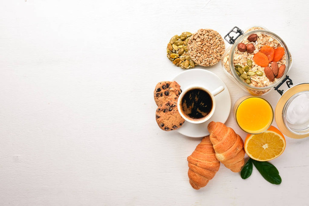 Un desayuno saludable. Zumo de naranja, kiwi, croissants, galletas, café, sobre una superficie de madera. Vista superior. Espacio libre para texto
. - Foto, Imagen