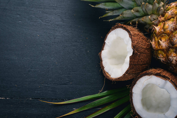 Coconut and pineapple on a wooden background. Tropical fruits and nuts. Top view. Free space for text. - Φωτογραφία, εικόνα