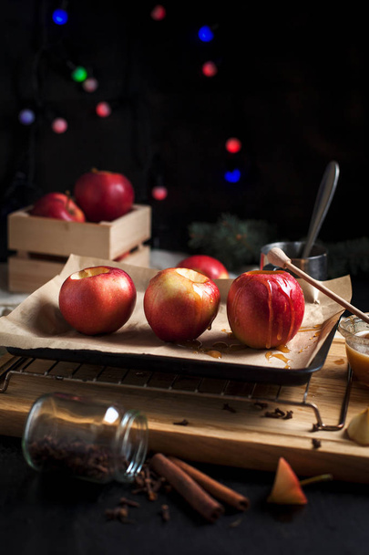 приготовление выпеченных яблок к новогодним праздникам, рождественских елок и новогодних огней, меда и корицы на деревянной разделочной доске на темном фоне
 - Фото, изображение