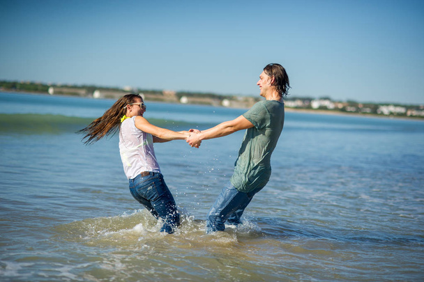 Happy young couple dances in the sea. - 写真・画像