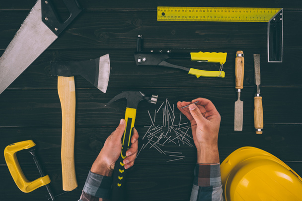 vista parcial del carpintero sosteniendo herramientas industriales en las manos
 - Foto, imagen
