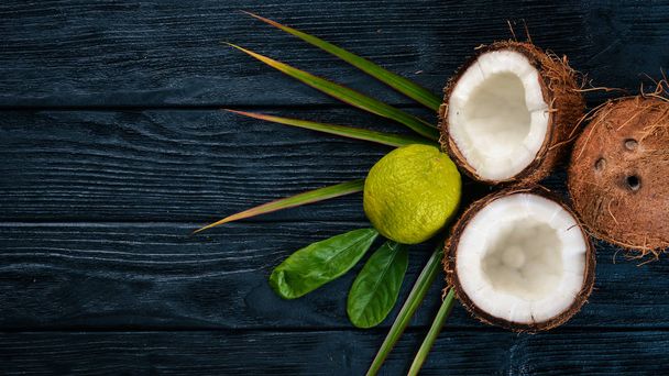 Coconut and lime. Fresh fruits. On a wooden background. Top view. Free space for text. - Foto, Imagem