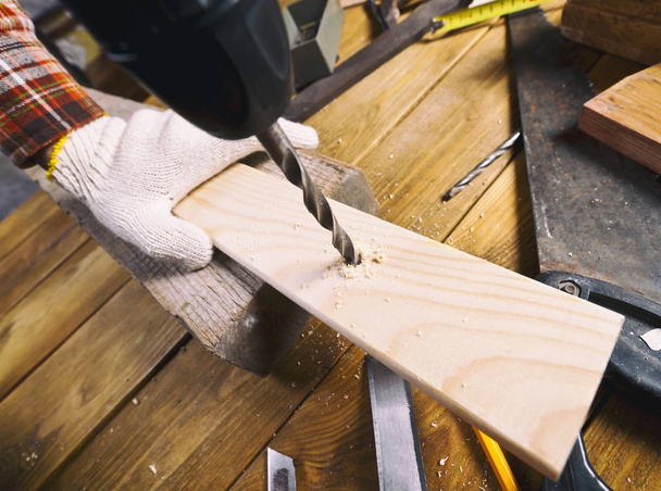 Man drills the wooden plank - Фото, изображение