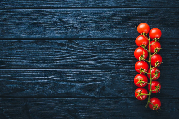 Cherry tomatoes on a twig on a wooden background. Top view. - Foto, Imagen