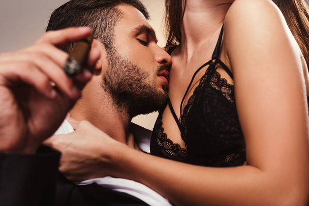 handsome businessman with cigar kissing beautiful girl in lingerie - Foto, imagen