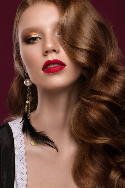 Beautiful redhair model: curls, bright gold makeup, jewelry and red lips. The beauty face. - Foto, imagen