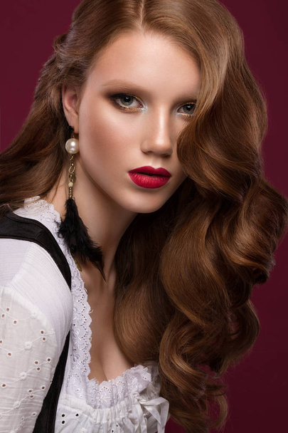 Beautiful redhair model: curls, bright gold makeup, jewelry and red lips. The beauty face. - Zdjęcie, obraz