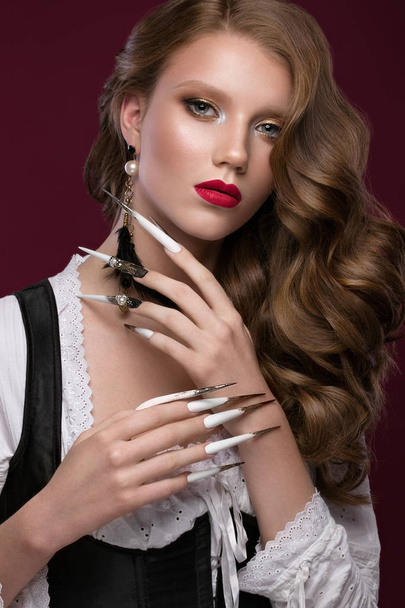 Beautiful redhair model: curls, bright gold makeup, long nails and red lips. The beauty face. Manicure disign - Photo, image