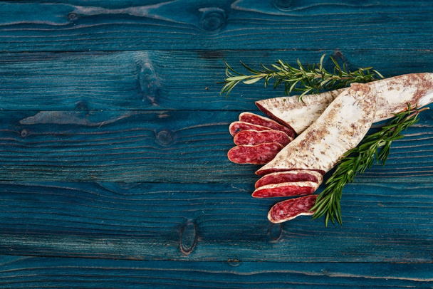 Fuet, Salami and Rosemary. Traditional Spanish sausage. On a blue wooden background. Top view. - Foto, immagini