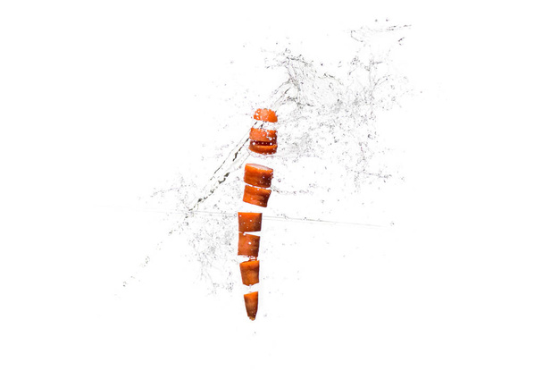 Φρέσκα φέτες καρότο σε πιτσιλιές νερού που απομονώνονται σε λευκό - Φωτογραφία, εικόνα