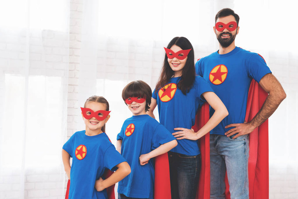 Young family in red and blue suits of superheroes. Their faces in masks and they are in raincoats. - Фото, зображення