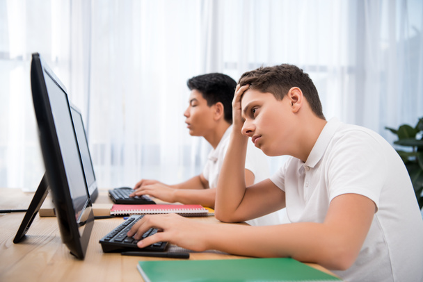 jóvenes chicos adolescentes cansados estudiando en computadoras
 - Foto, Imagen