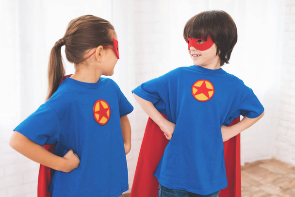 スーパー ヒーローの赤と青のスーツの子どもたち。彼らのマスク。子供たちの明るい部屋でポーズ. - 写真・画像
