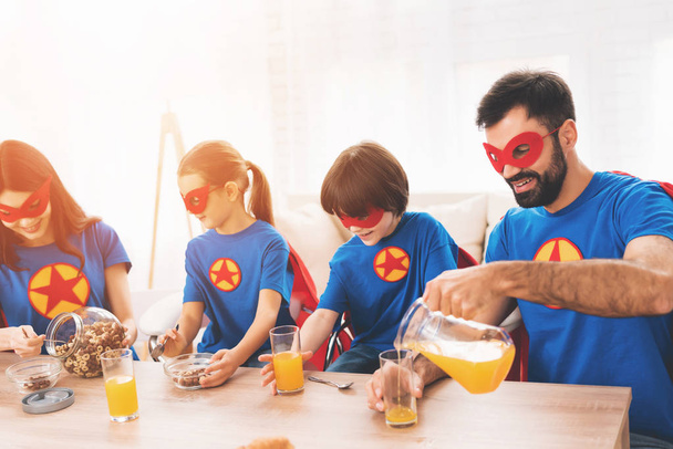 Young family in red and blue suits of superheroes. Their faces in masks and they are in raincoats. - Foto, Imagem