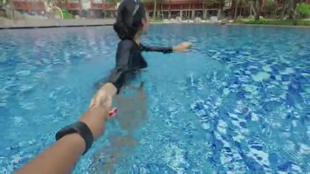 Happy young woman pulling her boyfriend hand and lead him to swim on the swimming pool - 映像、動画