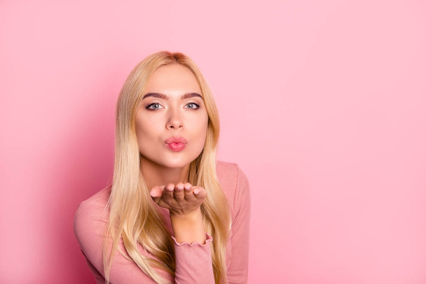 Close up portrait of young pretty woman sending kiss to the camera, standing over pink background - Foto, Bild