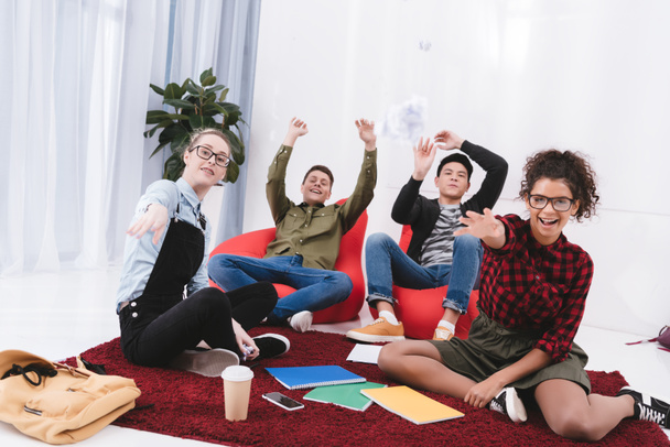 jeunes étudiants heureux assis et jetant du papier à la caméra
 - Photo, image