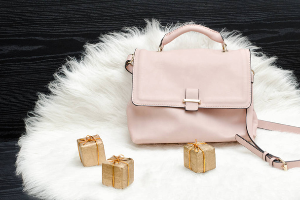 白の毛皮、黒テーブルの上のピンクのバッグ、ギフト ボックス。ファッショナブルな概念 - 写真・画像