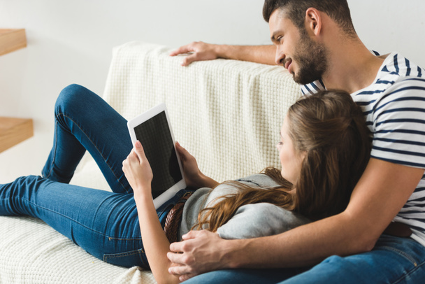 young couple using tablet together on couch at home - Foto, immagini