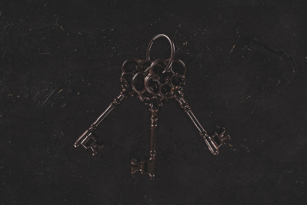 top view of vintage metal bunch of keys on black table - Foto, immagini