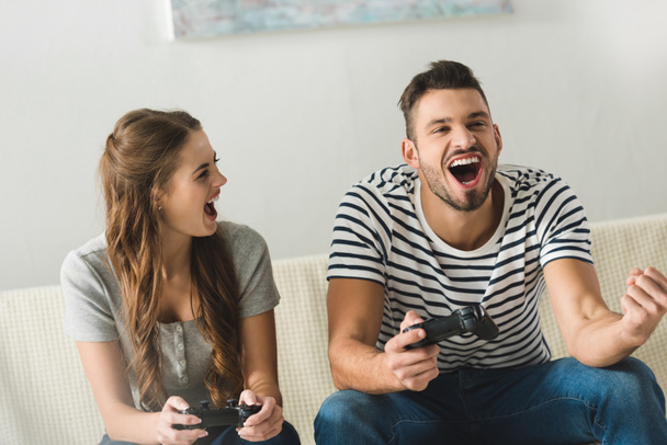 happy young couple playing games with gamepads at home - Foto, immagini
