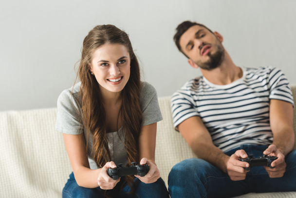 emotional young couple playing games with gamepads at home - 写真・画像