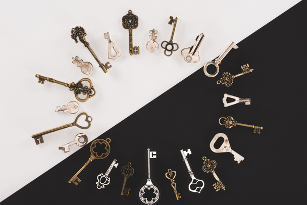 top view of different vintage keys circle frame over black and white background - Zdjęcie, obraz