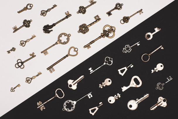 top view of different vintage keys over black and white background - Foto, Imagem