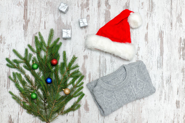 Weihnachtsmütze mit Tannenzweig und grauem Pullover auf Holzgrund - Foto, Bild