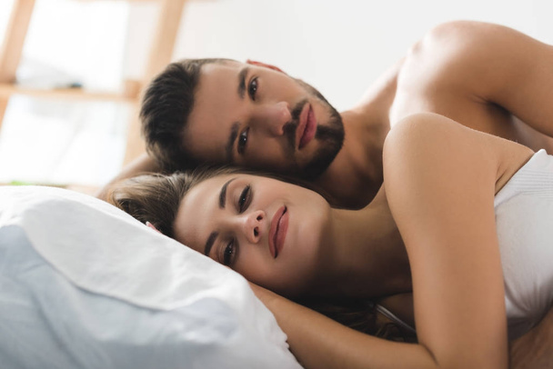 junges Paar entspannt sich morgens im Bett und schaut in die Kamera - Foto, Bild