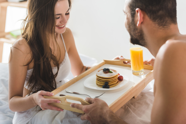 man giving breakfast in bed for beautiful happy girlfriend - Foto, afbeelding