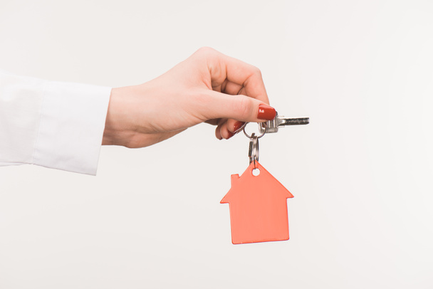 περικομμένη εικόνα θηλυκό χέρι που κρατά το κλειδί από το σπίτι που απομονώνονται σε λευκό - Φωτογραφία, εικόνα