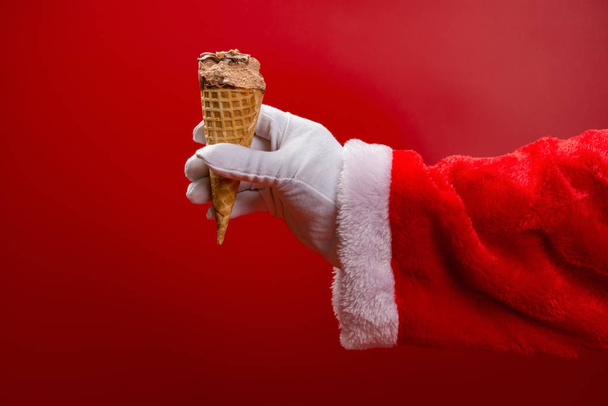 santa claus holding an ice cream cone with a bite on red - Photo, Image
