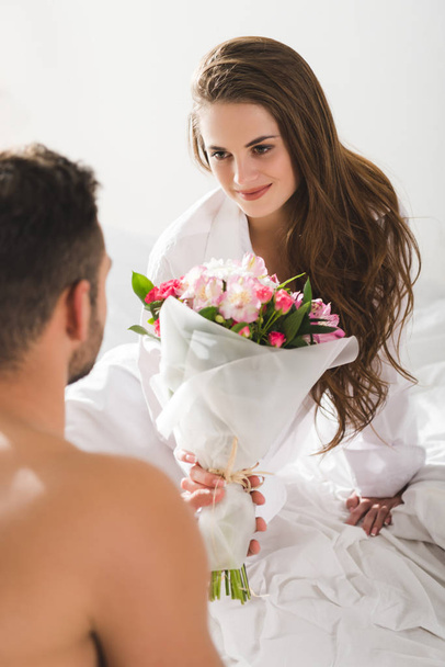 man presenting beautiful bouquet to girlfriend in morning in bed  - Photo, Image