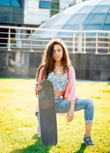 Young mixed race girl posing with skateboard outdoors - Фото, зображення