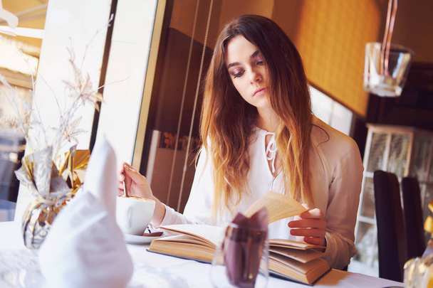 Young brunette reading a book in a restaurant - Fotografie, Obrázek