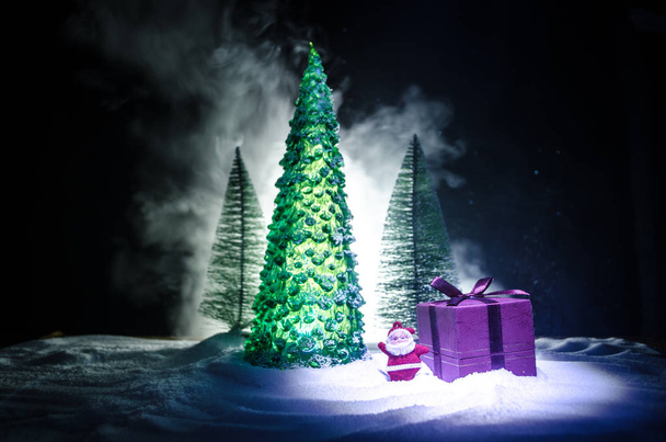 Red Christmas gift pole i jodła drzewa na śniegu. Boże Narodzenie dekoracji wnętrz z śniegu i drzewa na ciemnym tle z miejsca kopii - Zdjęcie, obraz
