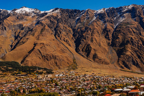 view of the high Caucasian snow-capped mountains, a small town, many houses - Photo, image