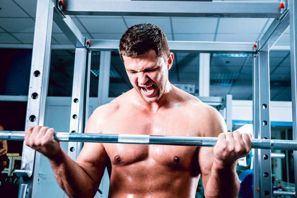 Young muscular man in the gym with barbell - Photo, Image