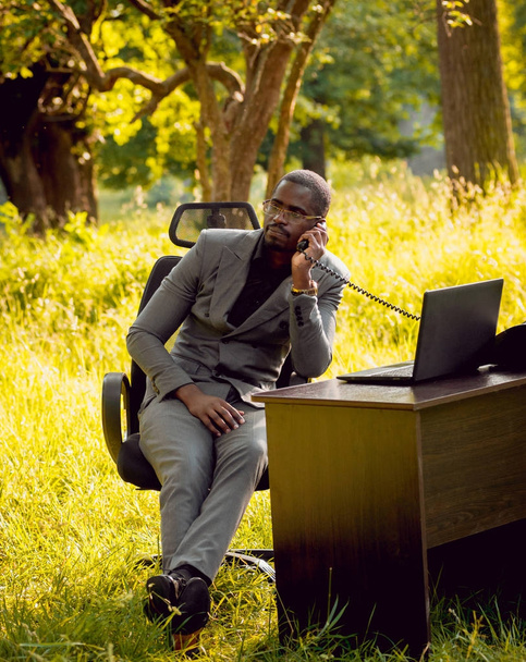 Giovane uomo d'affari afroamericano al lavoro nel parco. Concetto di lavoro a distanza
. - Foto, immagini
