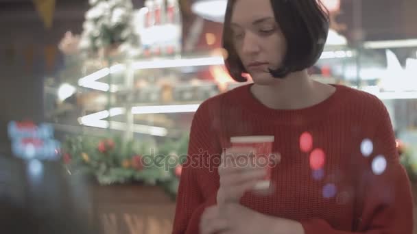 Retrato de jovem mulher atraente usando smartphone sentado no café. Tempo de Natal
 - Filmagem, Vídeo