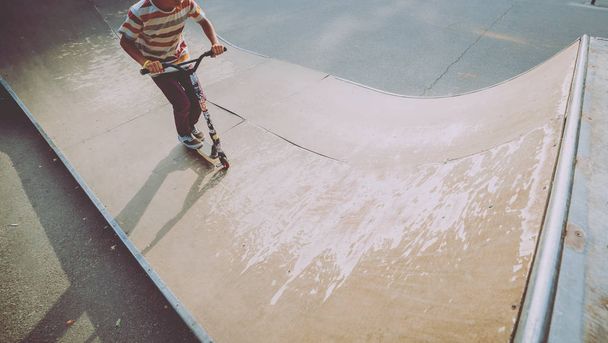 Boy riding a kick scooter in skate park - Φωτογραφία, εικόνα
