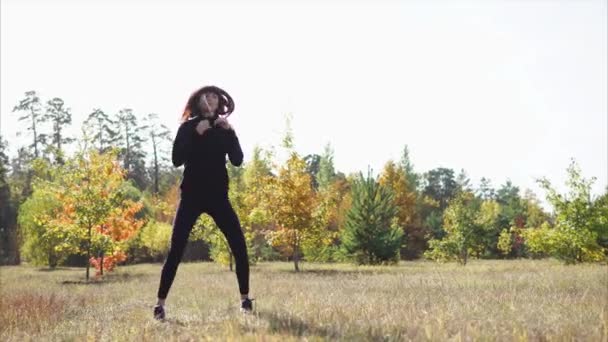 Young sporty woman is doing daily work-out, jumping outdoors in early fall - Footage, Video
