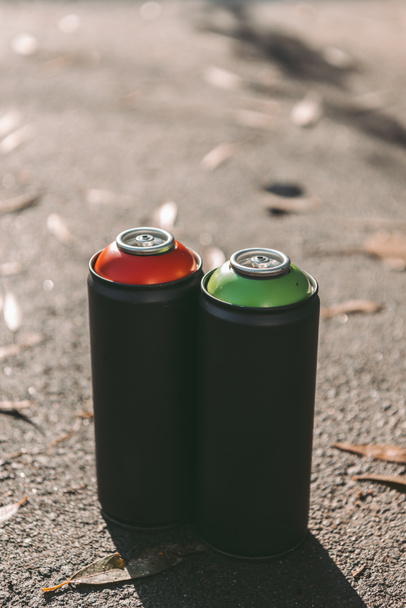 latas com tinta aerossol vermelha e verde para grafite em asfalto
 - Foto, Imagem