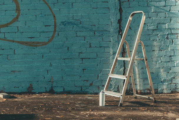 ladder en kan met kleurrijke verf in de buurt van de muur - Foto, afbeelding